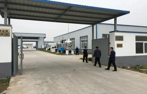 厂区大门敞开，内部可见厂房与水处理设备，几名人员正在厂区内行走查看
